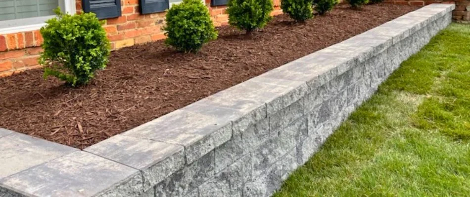 Stone retaining wall with a mulch bed and plants in Bristow, VA.